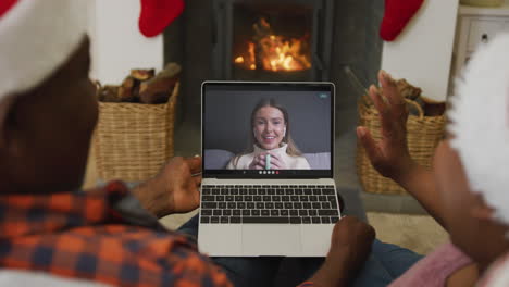 Pareja-Afroamericana-Con-Sombreros-De-Santa-Usando-Una-Computadora-Portátil-Para-Una-Videollamada-Navideña-Con-Una-Mujer-En-La-Pantalla