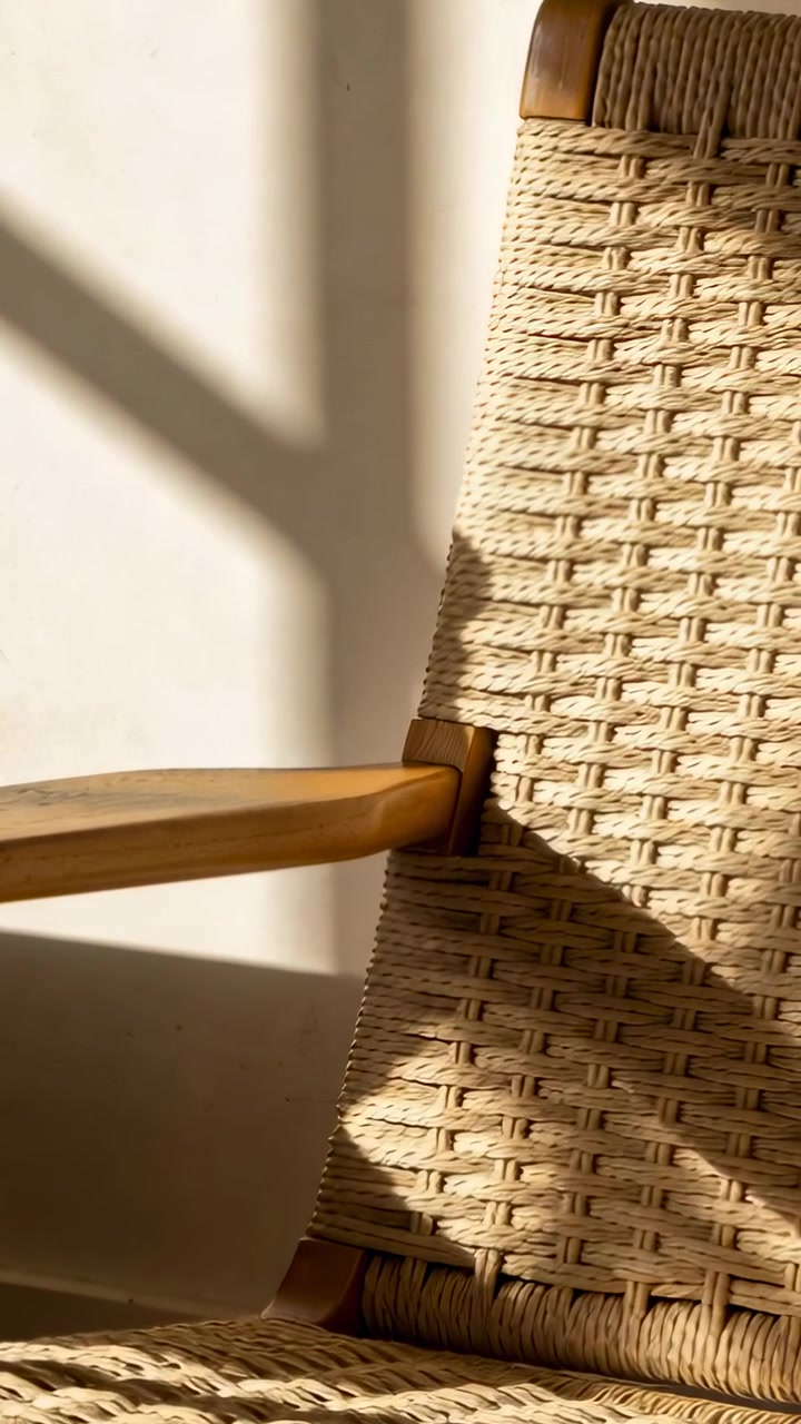 Vertical video: Shifting sunlight moving over woven chair wood armrest corner, showing shadow shift
