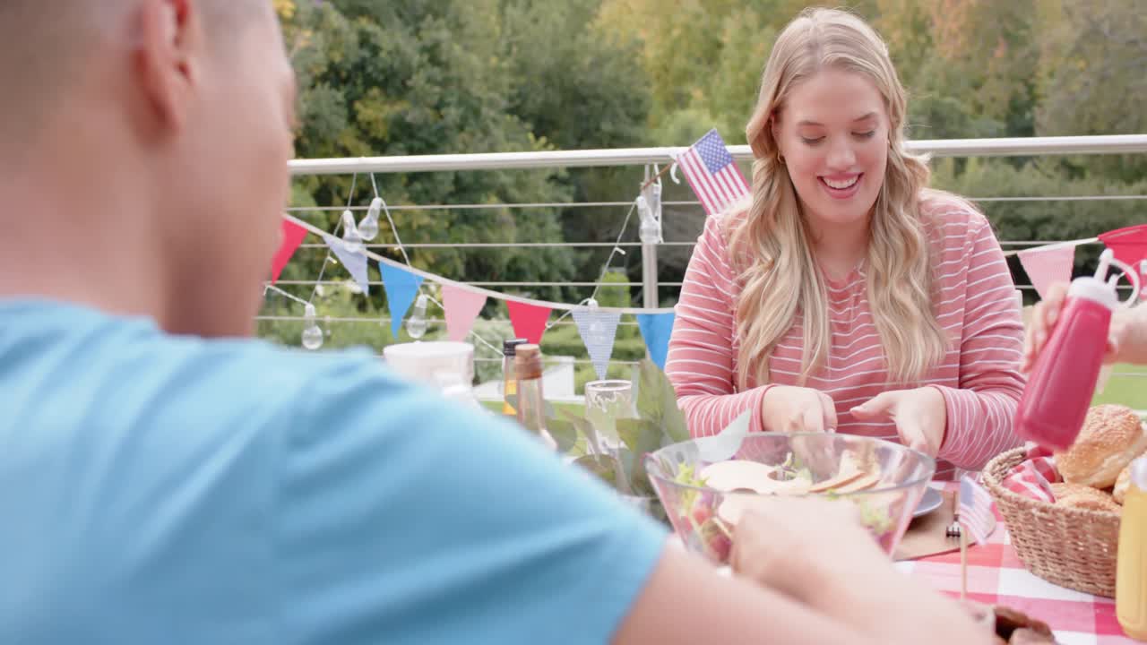 정원에서 저녁 식사 테이블에서 먹고 얘기하는 다양한 친구들의 행복한 그룹, 느린 움직임