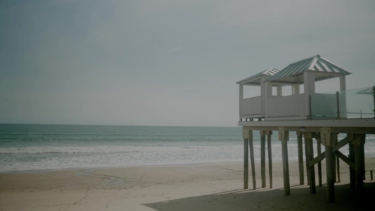 Dermaga yang tenang di Pantai Salisbury, Massachusetts, menghadap perairan tenang dan ombak di kejauhan, statis