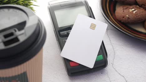 payment terminal with credit card, coffee, and cookies