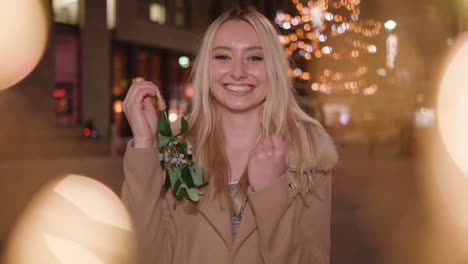 pretty lady beckons you closer to have a kiss under the mistletoe