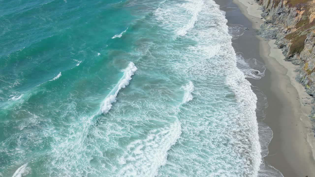Un drone riprende una vista completa dall'alto di onde che si infrangono sulla riva sabbiosa di Black Point Beach, California.