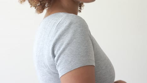 Mittelteil-Einer-Afroamerikanischen-Frau,-Die-Ein-Graues-T-Shirt-Mit-Kopierraum-Auf-Weißem-Hintergrund-Trägt