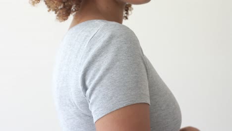 sección media de una mujer afroamericana vestida con una camiseta gris con espacio de copia en un fondo blanco