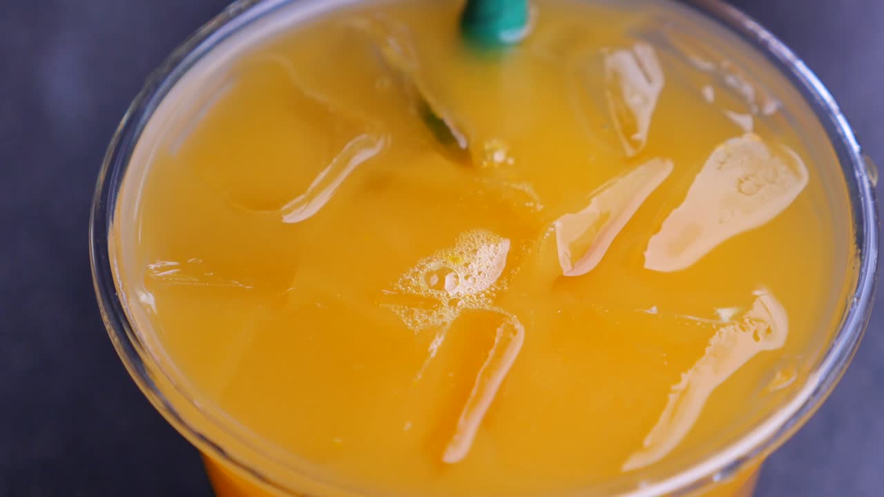 jugo de naranja en una taza de plástico con hielo