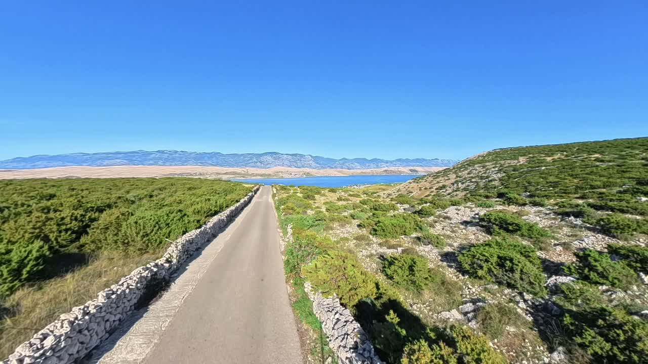 Sunny rural road on Pag Island, Croatia, filmed with Insta360 X5 from a high viewpoint. Traditional stone walls, Adriatic Sea, and rugged island landscape in wide perspective