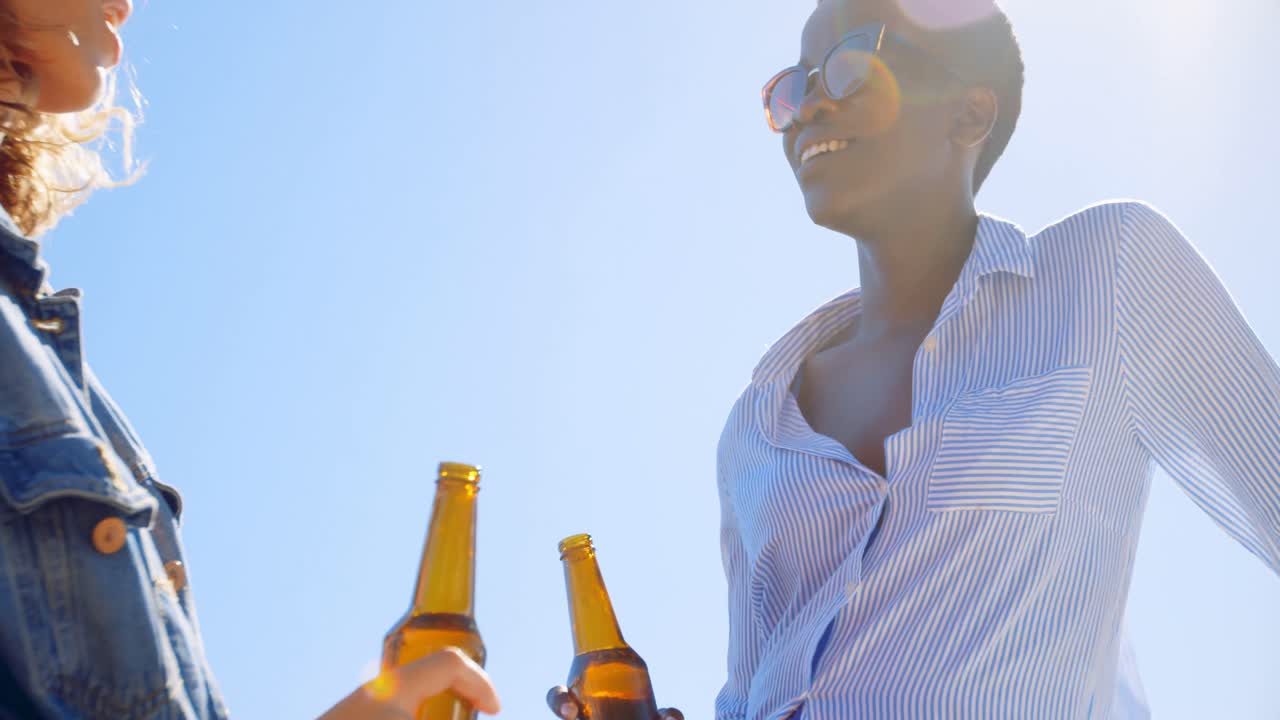 Female friends interacting with each in the beach 4k