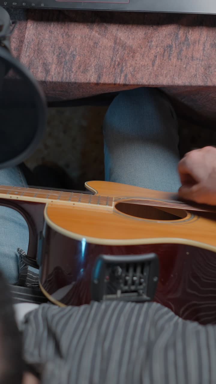 Close-up of a person playing an acoustic guitar in a recording setting