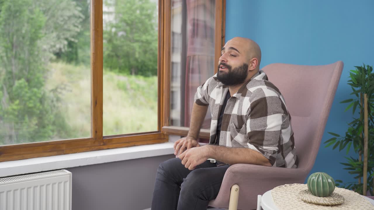 un hombre feliz y pacífico. está sentado frente a la ventana.
