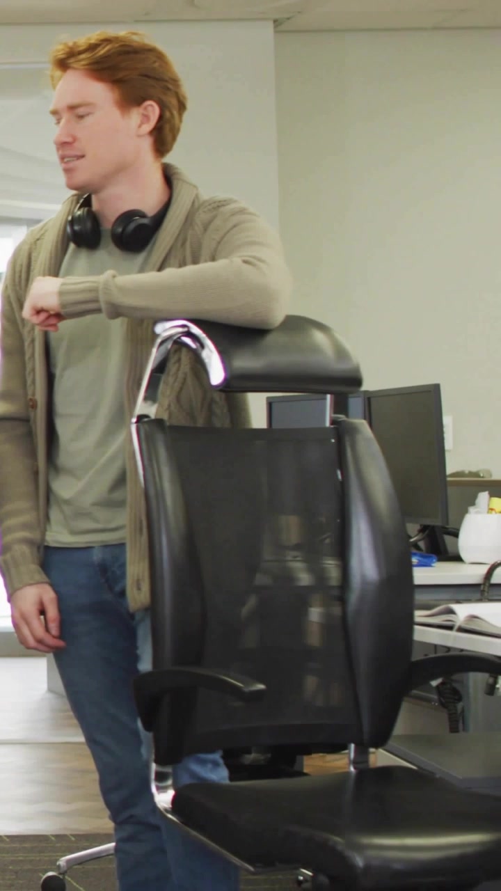Vertical video: Office worker tapping wrist causing social badges over chair, checking metrics