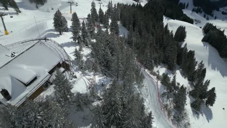 Aerial-drone-bird's-eye-view-over-chairlift-along-the-slope-at-Engelberg-Brunni-bahnen-along-the-Swiss-alps-in-Switzerland-on-a-snowy-cold-winter-day