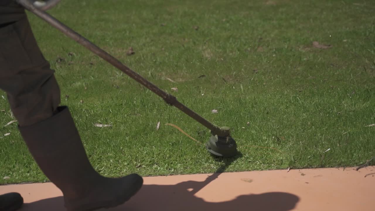 jardinería_primer plano de la desbrozadora o cortadora de malezas utilizada por el jardinero sobre la hierba en un día soleado
