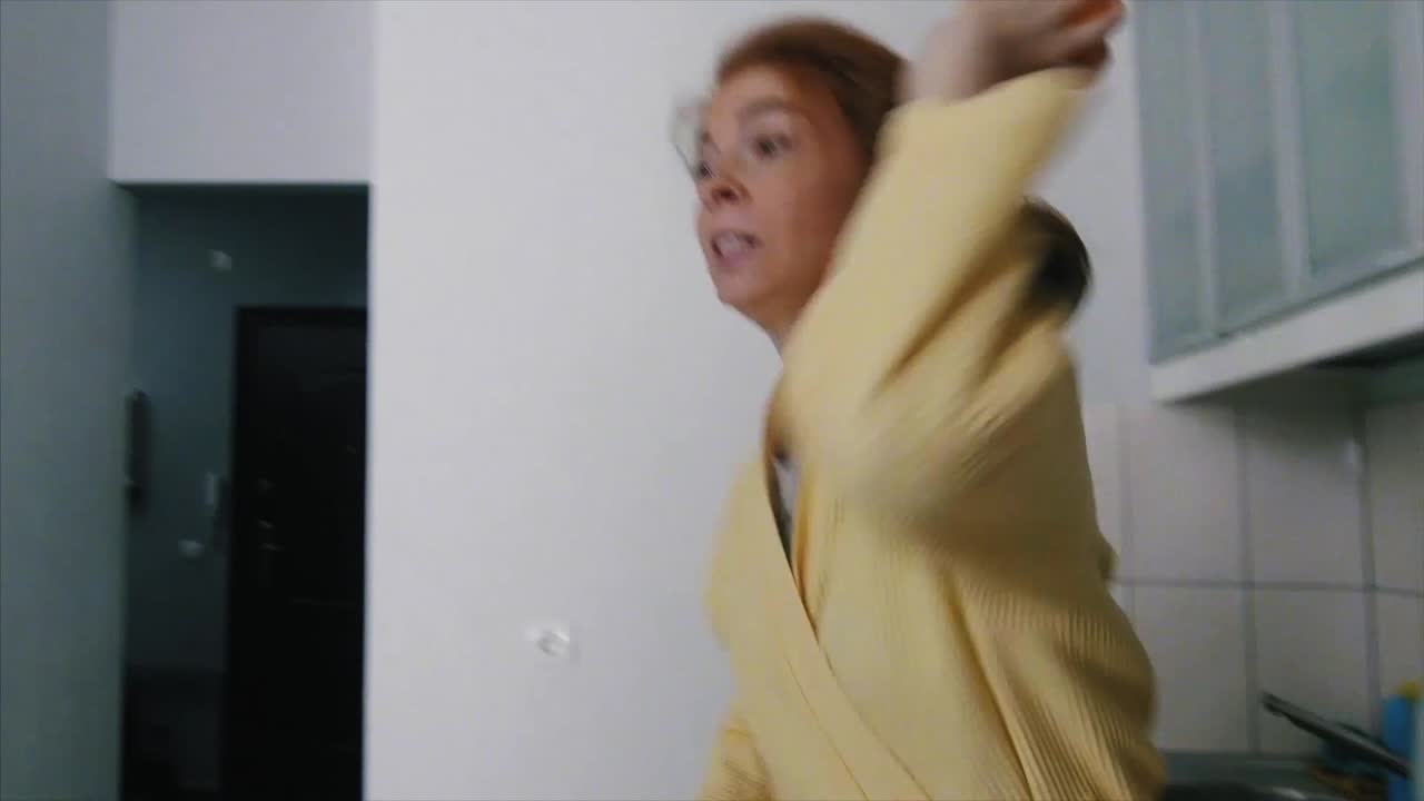 Woman in a bathrobe moving around in an apartment