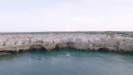 aerial flyover the sea towards the town of polignano a mare , italy