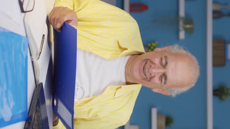 Vertical-video-of-Home-office-worker-old-man-looking-at-paperwork-files.