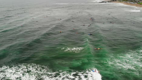 drone capturing a lot of people surfing near the canggu beach, bali