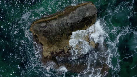 overhead view of crashing waves over outcrop on turquoise sea