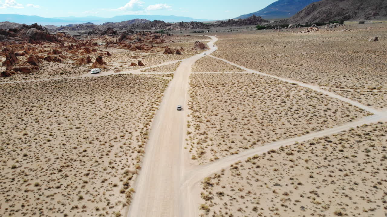 Aerial shot following a car down a dirt road in the Alabama Hills of the Sierra Nevada Mountain Range in California USA