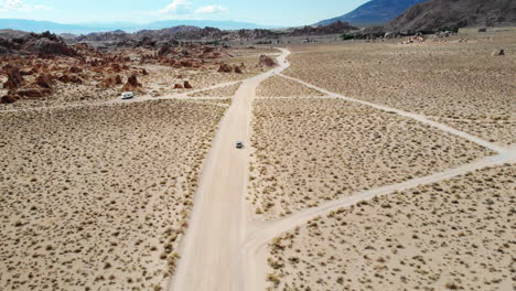 aerial shot following a car down a dirt road in the alabama hills of the sierra nevada mountain range in california usa