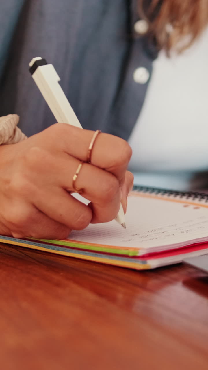 Primo piano di una mano che scrive appunti su un quaderno a spirale