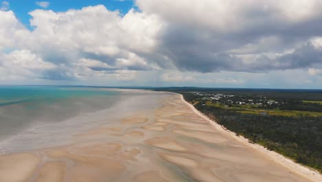 alto, vuele sobre una hermosa costa de marea baja donde las venas de agua se extienden entre las diversas dunas de arena blanca y cremosa bajo un cielo deliciosamente azul que alberga grandes nubes blancas y esponjosas