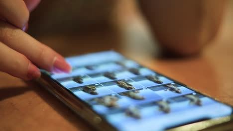 slow motion close-up shot of a female with pink nails scrolling through hundreds of pictures of her phone