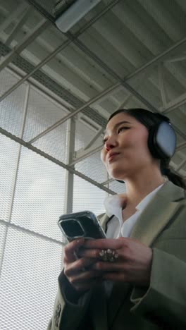 mujer usando teléfono y auriculares en una estación