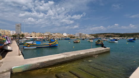 static wide shot of marsaxlokk fishing village with colorful boats in malta