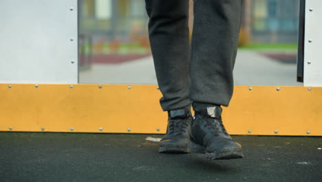 leg view of someone walking into a sports arena, showcasing lower body and footwear on vibrant yellow boundary line, with blurred urban background