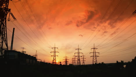 red sunrise with power lines. hydro transmission lines and towers making up the electricity grid. panoramic view of eletric towers at sunset. motion camera back.