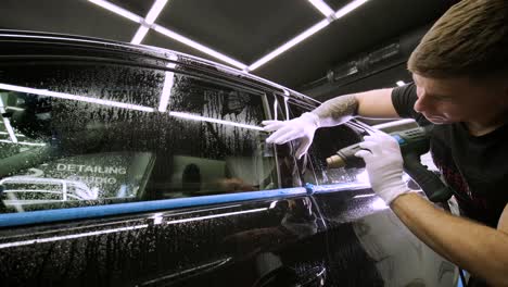 hombre que cubre el coche con cinta de poliuretano de vinilo. películas para el coche. pegatina película protectora en el coche