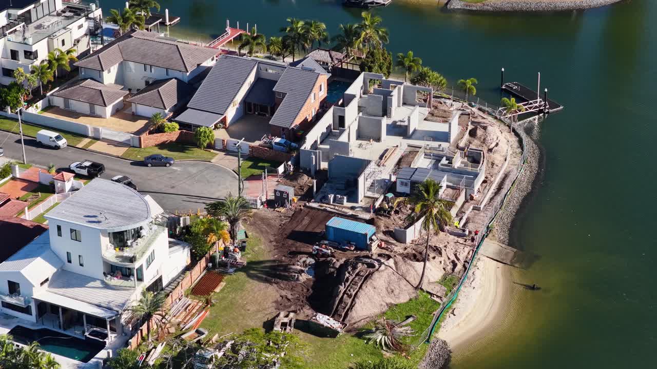Drone footage captures construction activity along a waterfront in Gold Coast, Australia, highlighting residential development and machinery in action