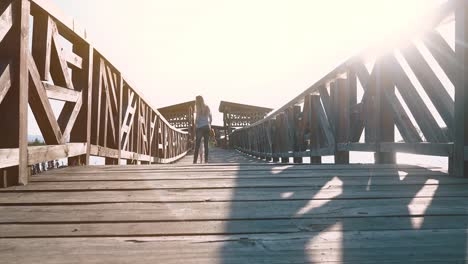 Junge-Schöne-Mutter-Geht-Mit-Einem-Kind-Bei-Sonnenuntergang-Auf-Eine-Holzbrücke