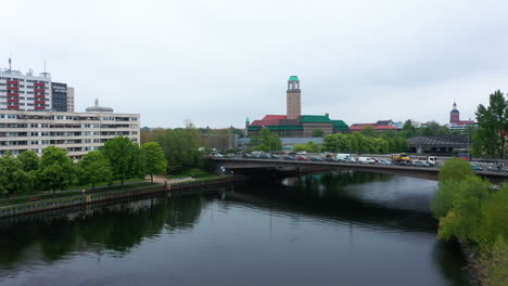 Flight-above-water-surface-of-Havel-river,-fly-over-road-bridge-and-reveal-train-station-near-Rathaus-Spandau.-Old-city-hall-building-with-tall-lookout-tower.-Berlin,-Germany