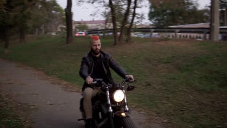 portrait of a smiling man with orange iroquois rides a bike in the city