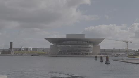 the opera house in copenhagen denmark seen from across the river on a cloudy day log
