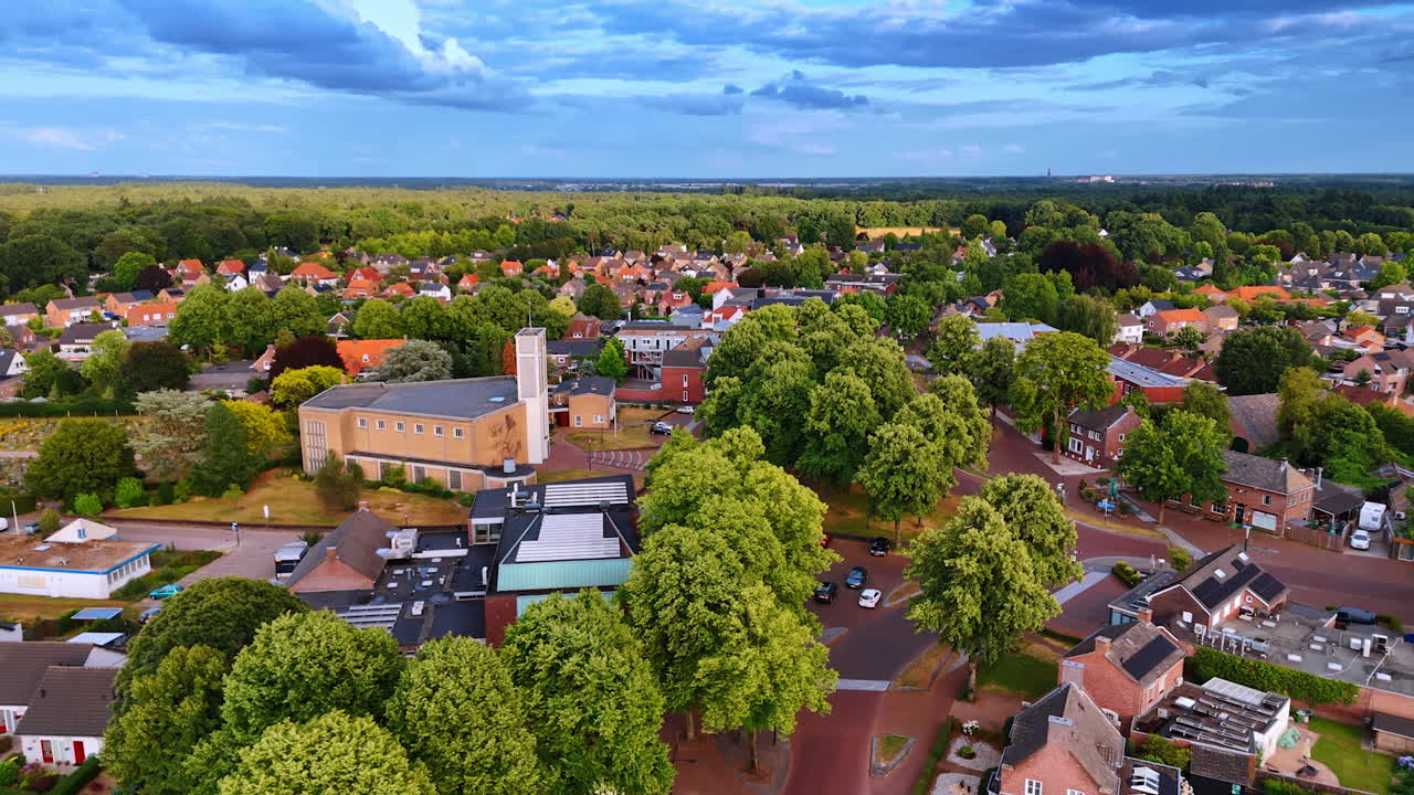 Village blocks surrounded by greenery. A drone panorama of Dutch village blocks immersed in thick tree cover