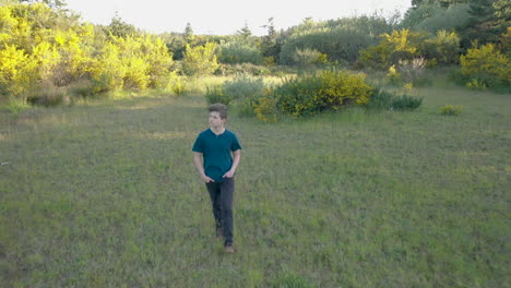 handsome teenage boy walking through beautiful green surroundings, with his hands in his pockets