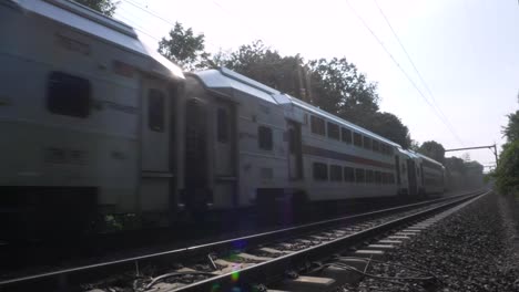 slow motion: end of commuter train, close up, as it passes by on the train tracks and leaves frame