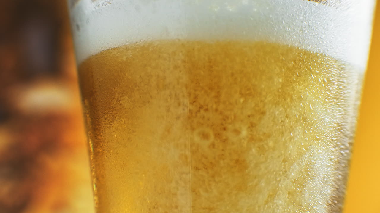 close-up cámara lenta: cerveza fría en un vaso grandes gotas y burbujas en la cerveza