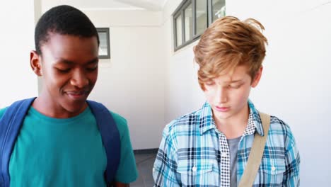 schoolboys reading book while walking in corridor