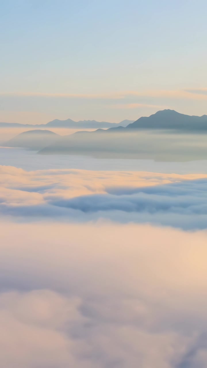 Vertical video: Shifting cloud deck revealing mountain ridge at mountain overlook, sunrise warming