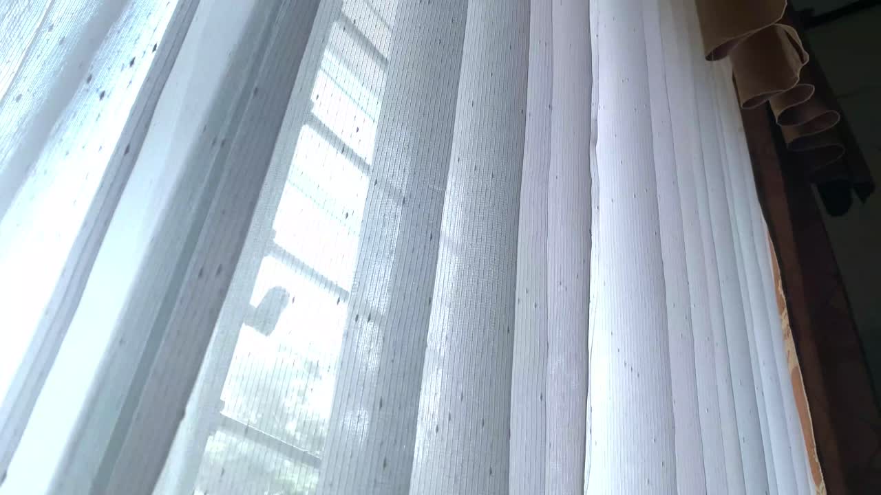 las cortinas blancas en las ventanas de la casa se mueven en el viento