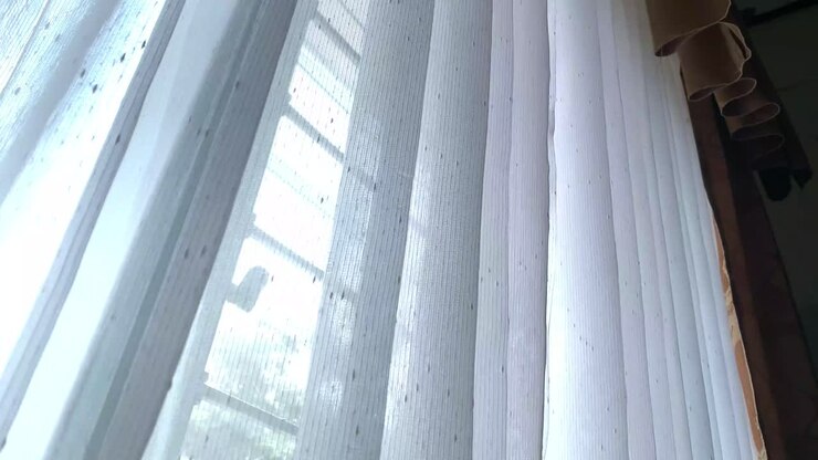 Le tende bianche alle finestre della casa si muovono al vento
