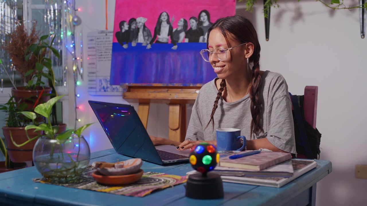 Joven estudiante en su computadora, desplazándose y luego riendo.