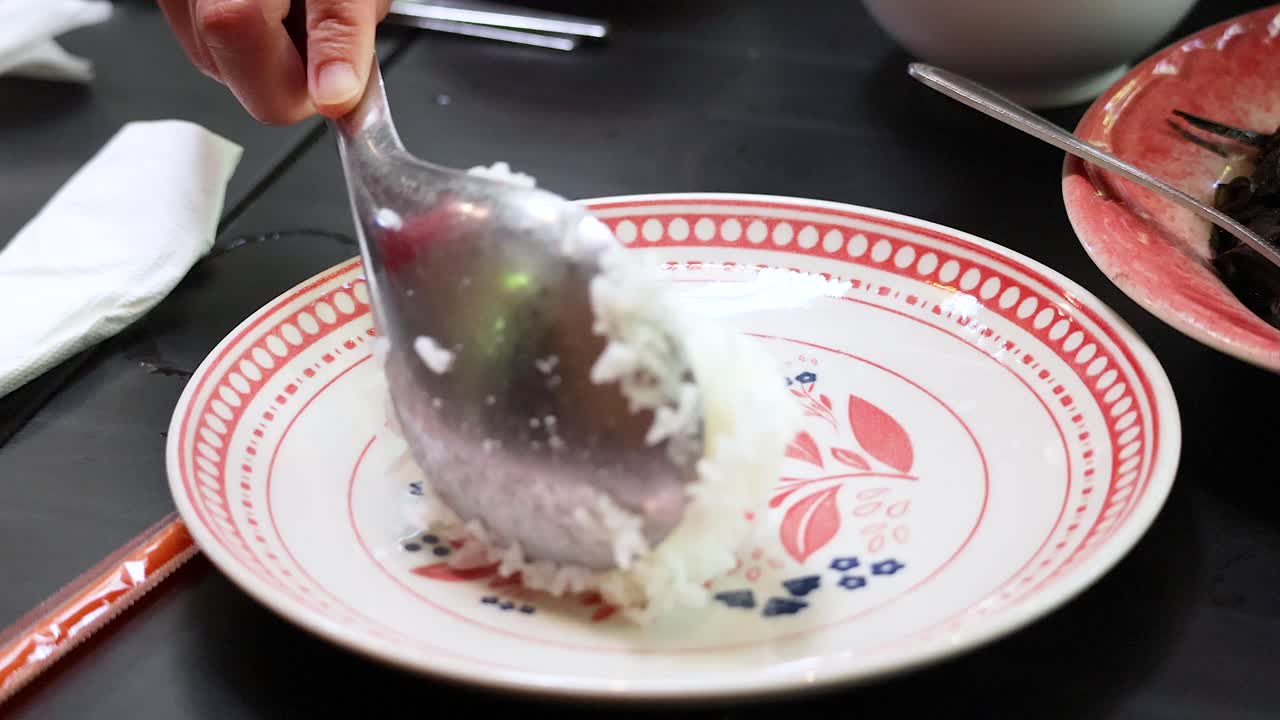 recogiendo arroz cocido en un plato decorativo en la mesa de comedor