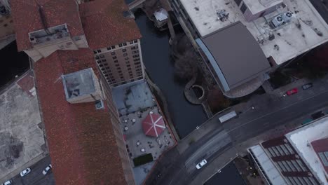 a top-down drone shot captures a winding river flowing through the city, with bridges crossing and reflections shimmering.