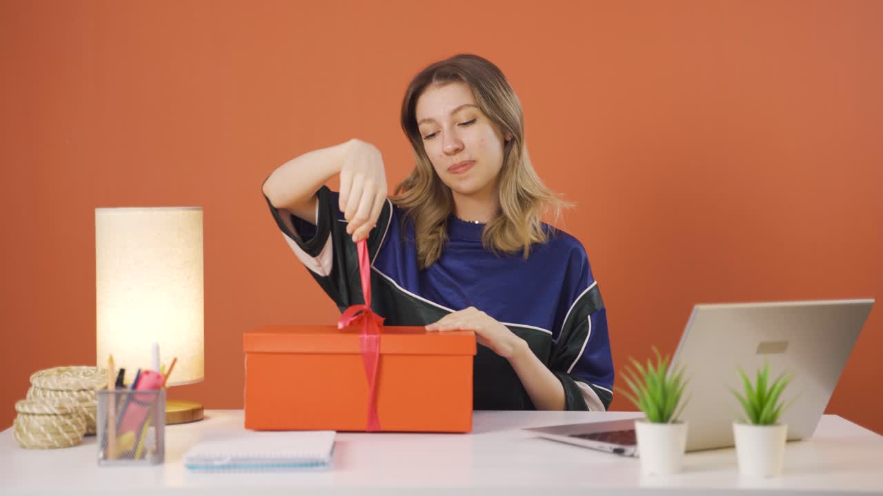 幸せで喜びに満ちた若い女性が贈り物の包みを開けている