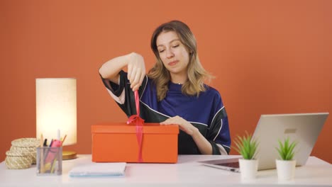 una joven feliz y alegre abriendo un paquete de regalos.